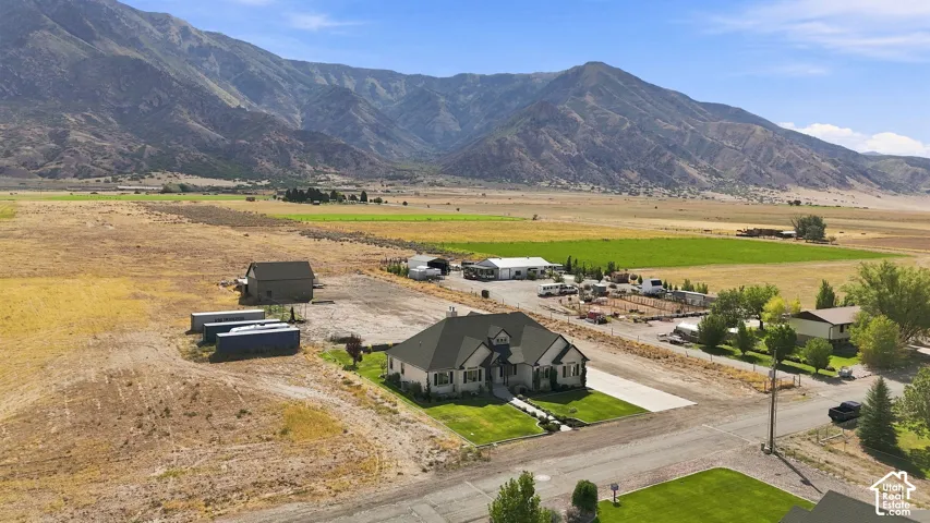 Expansive acreage featuring a multi-structure property, detached storage building, manicured lawn, and mountain backdrop