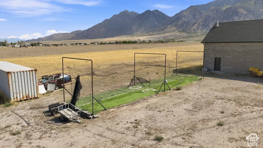 Expansive exterior lot featuring artificial turf batting cages, masonry structure, and panoramic mountain backdrop