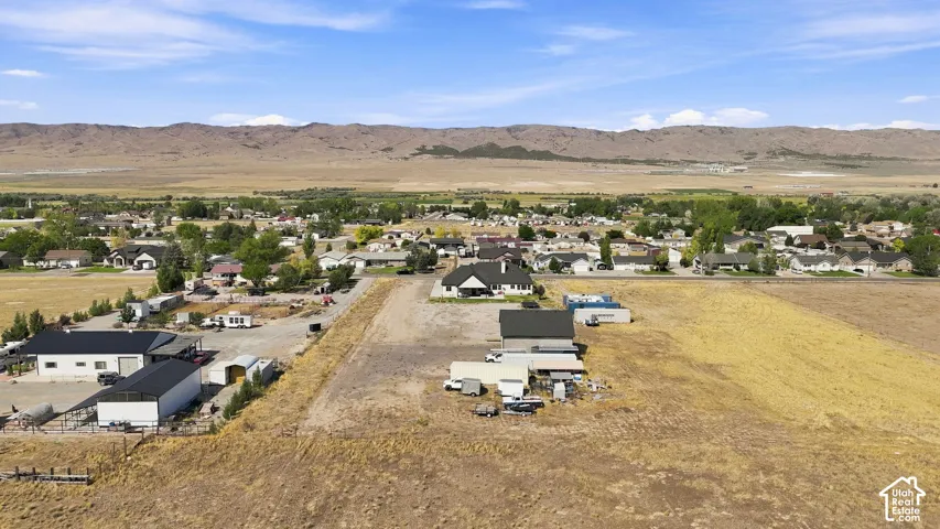 Aerial perspective of expansive acreage featuring multiple detached outbuildings and a backdrop of mountain scenery