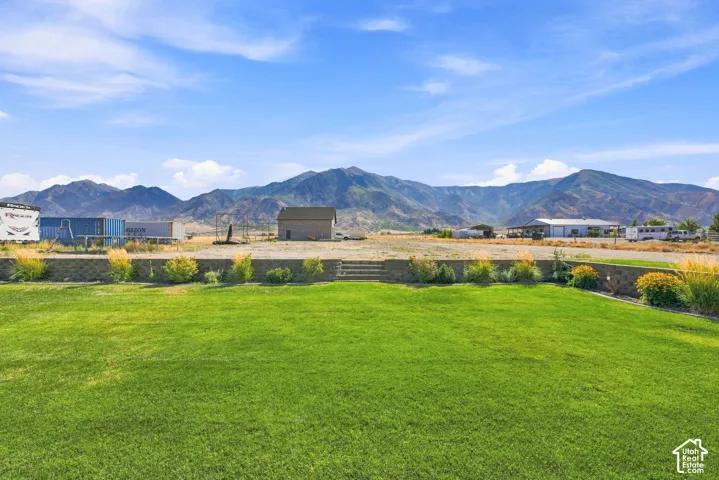 Expansive lawn with stone-block retaining wall, integrated stone steps, and prominent mountain backdrop