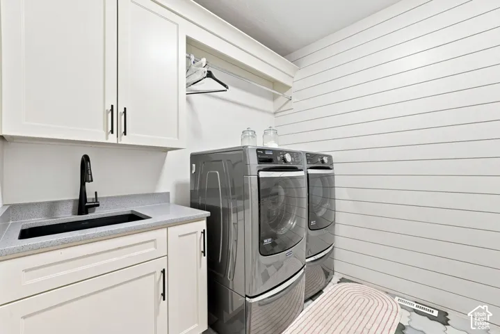 Laundry room featuring white cabinetry, a built-in utility sink with a matte black faucet, solid-surface countertops, shiplap wall paneling, and an integrated hanging rod