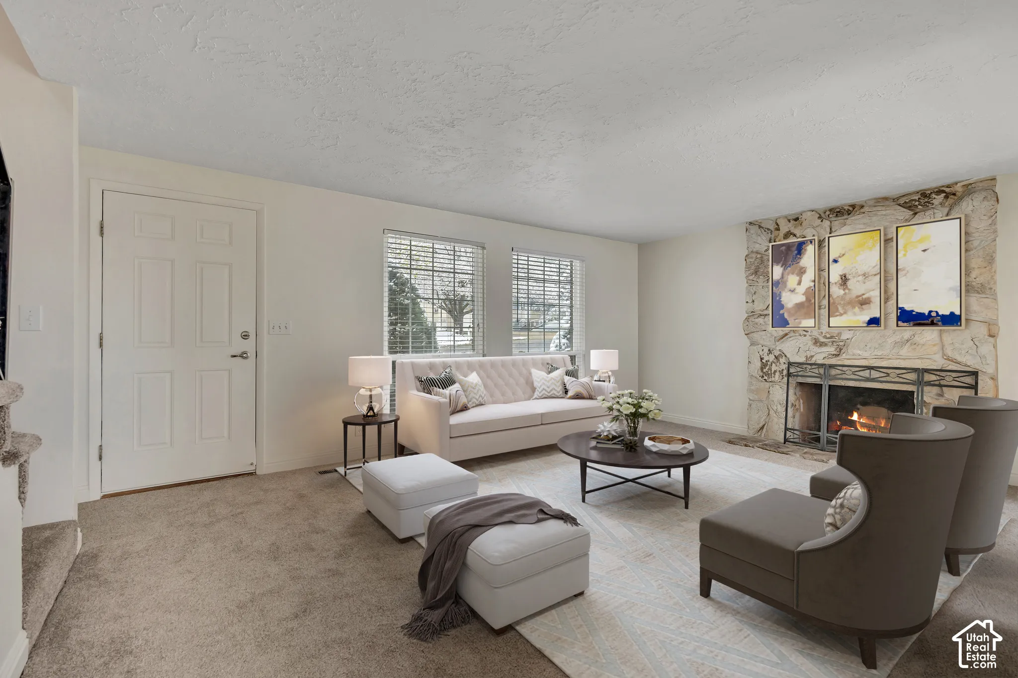 Stone-clad fireplace with a metal grate, textured ceiling, and a multi-pane window with blinds