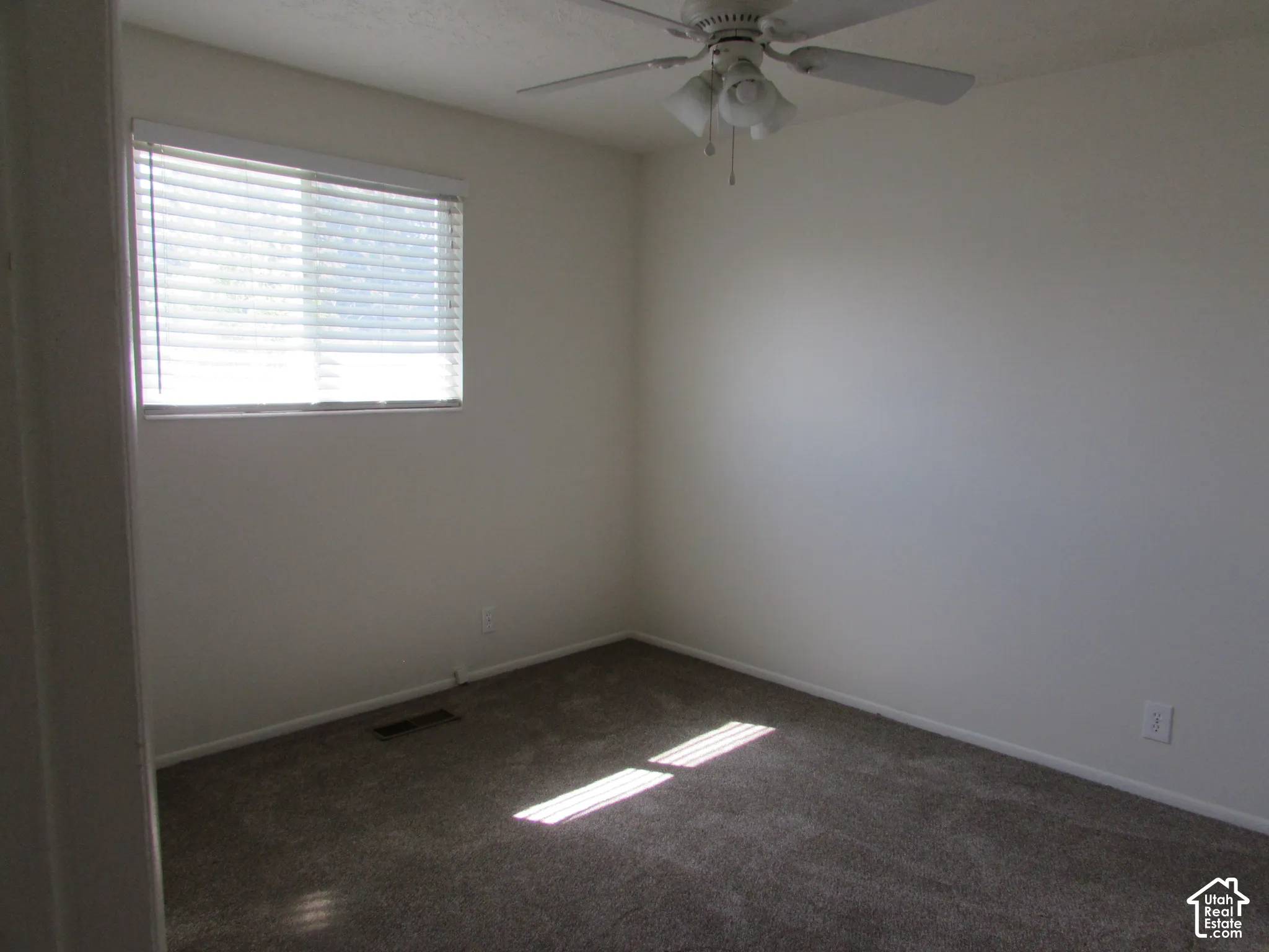 Neutral wall paint, ceiling fan with integrated lighting, carpeted flooring, and a window with blinds