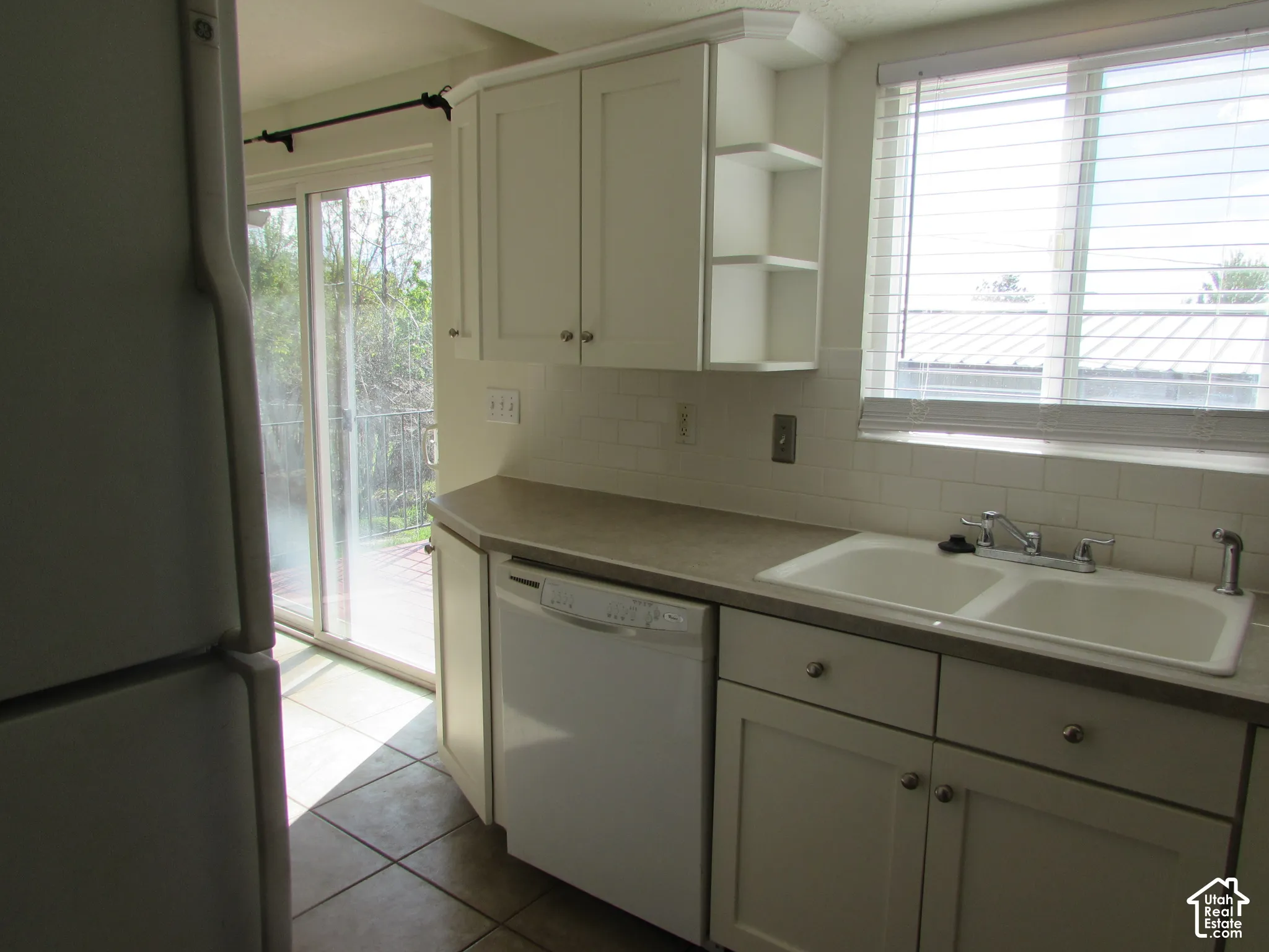 Kitchen featuring white cabinetry, subway tile backsplash, and a double basin sink