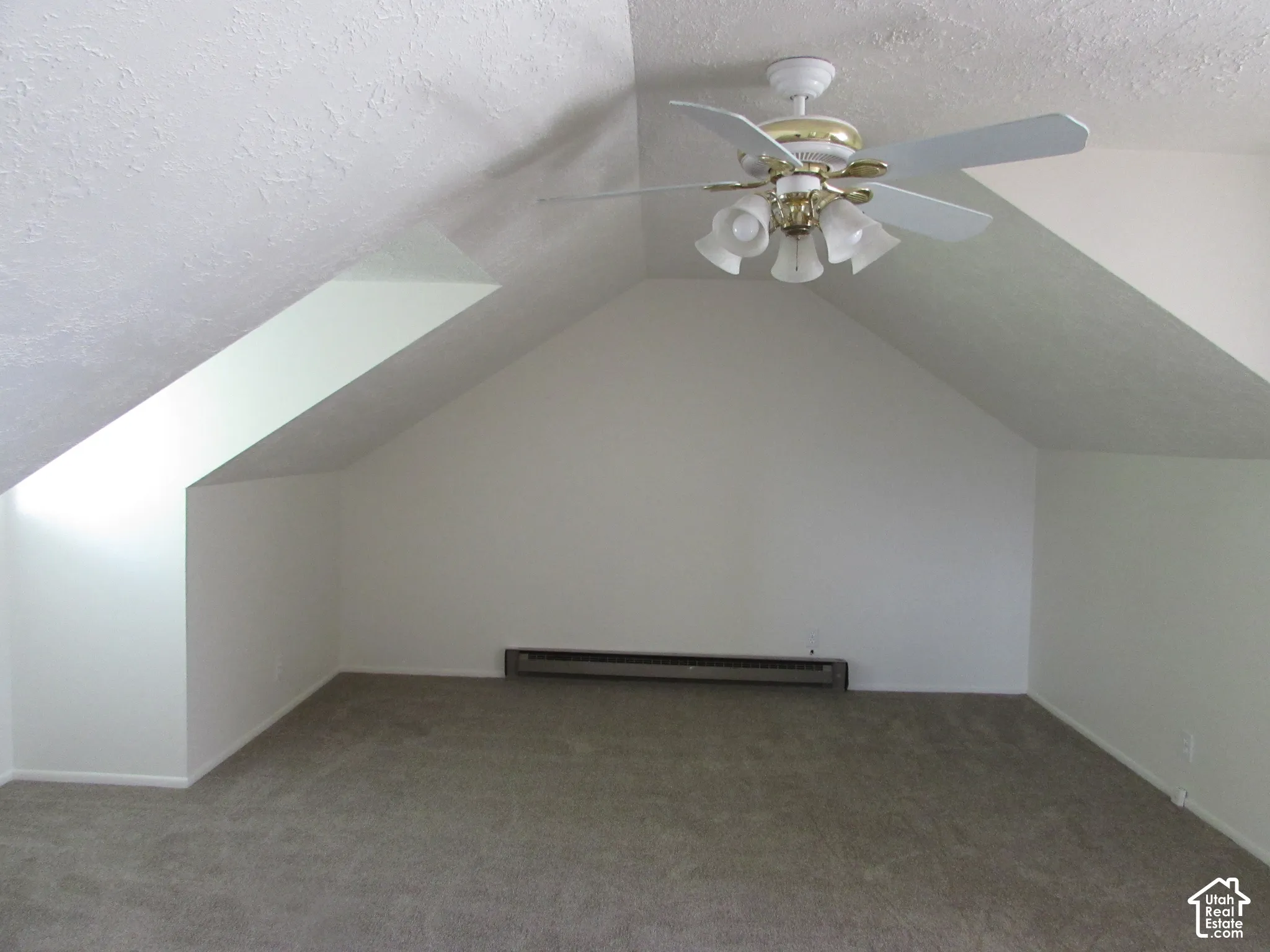 Vaulted ceiling with a ceiling fan, neutral carpeting, and white walls