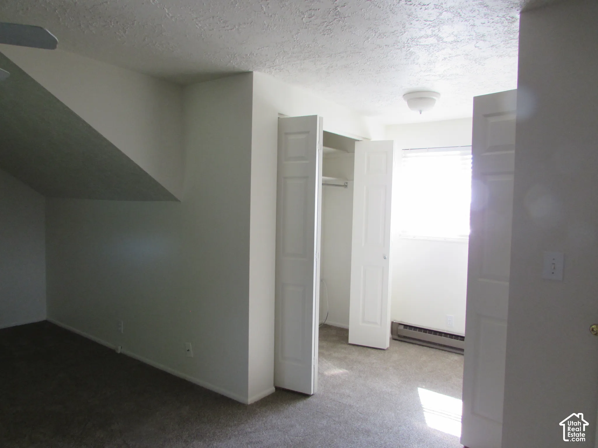 Carpeted room with a ceiling fan, built-in closet with bi-fold doors, and a window with blinds