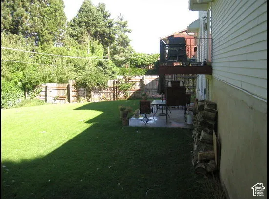 Expansive green lawn with a wooden perimeter fence and mature trees