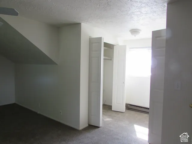 Carpeted room with a ceiling fan, built-in closet with bi-fold doors, and a window with blinds