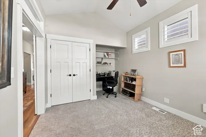 Vaulted ceiling, double-door closet, built-in shelving, carpeted flooring, and window shutters