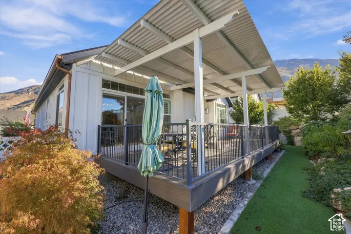Elevated deck featuring a covered metal patio roof, dark metal railings, and synthetic composite decking, complemented by mountain scenery
