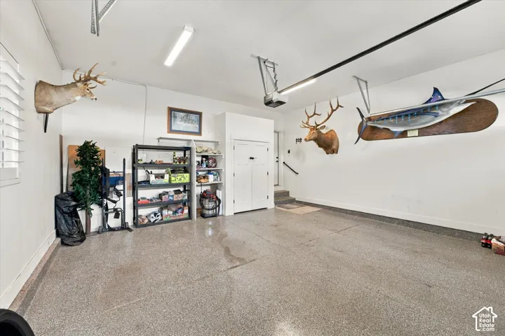 Attached multi-car garage featuring epoxy flooring, built-in shelving, white double-door storage, and overhead lighting