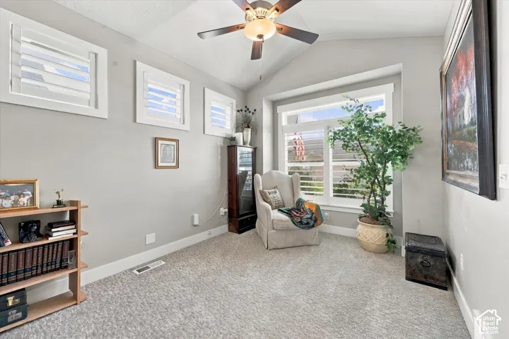 Vaulted ceiling featuring a central light fixture with an integrated ceiling fan, large picture window with plantation shutters, and triple transom windows