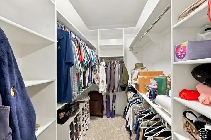 Walk-in closet featuring white built-in shelving, multiple hanging rods, and dedicated cubby storage