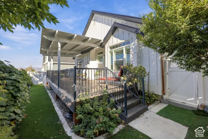 Exterior featuring board-and-batten siding, a covered deck with metal railings, a staircase, and a gated side entrance