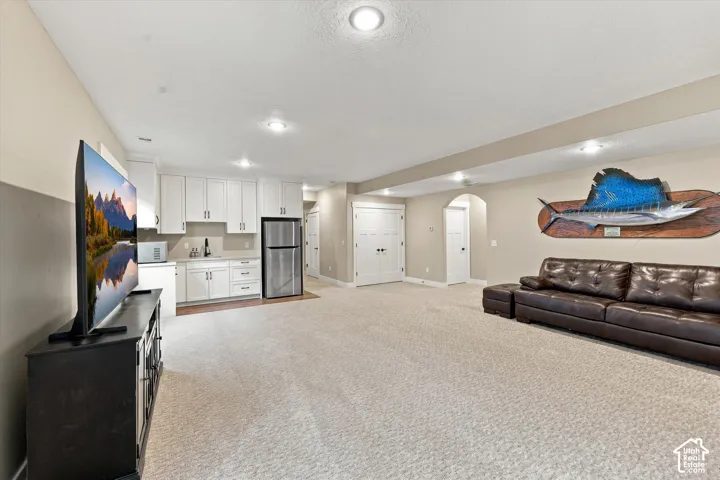 Kitchenette featuring white cabinetry, stainless steel refrigerator, and sink