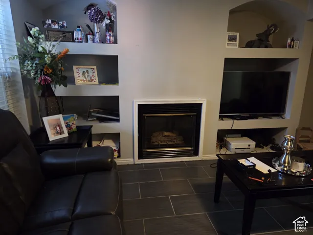Fireplace with a black metal surround and white trim, paired with recessed shelving units featuring arched header details and large-format tile flooring
