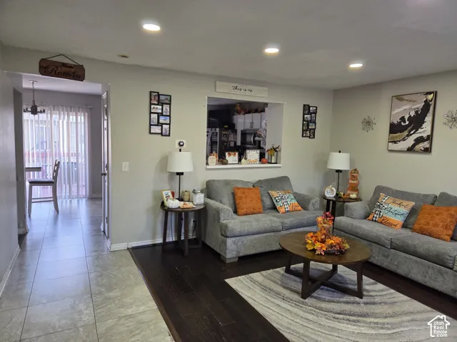 Recessed lighting, dark wood-finish flooring, and pass-through window to the kitchen