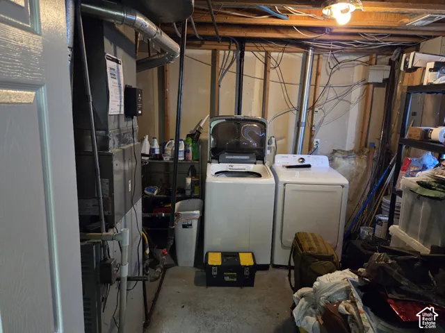 Utility area featuring a forced-air furnace, exposed stud framing, and laundry hookups