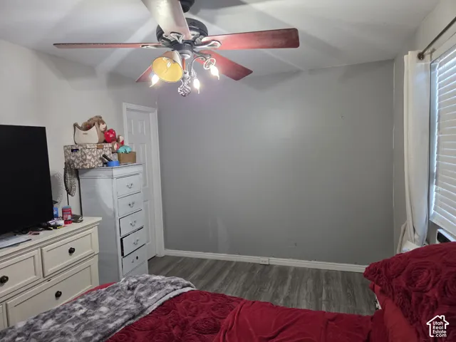 Room featuring wood-finish flooring, a multi-light ceiling fan, and a neutral-toned accent wall