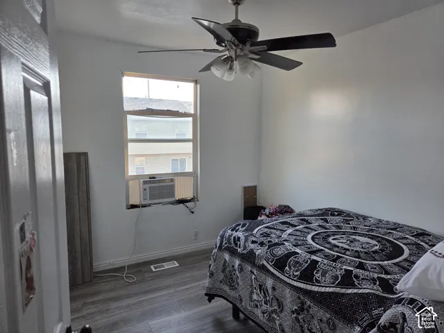 Room featuring wood-finish flooring, a multi-blade ceiling fan with integrated lighting, and a single-hung window