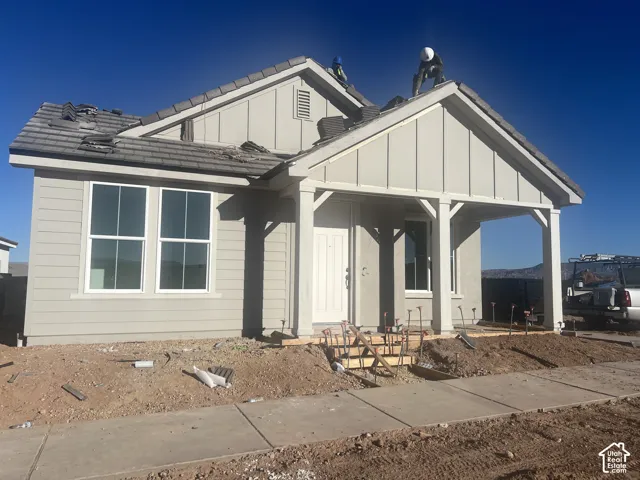 Single-story exterior featuring composite siding, board and batten gable detailing, a covered front porch with squared columns, and a concrete tile roof