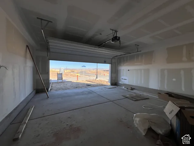 Two-car garage featuring a concrete slab floor, unfinished drywall, and an overhead automatic garage door opener