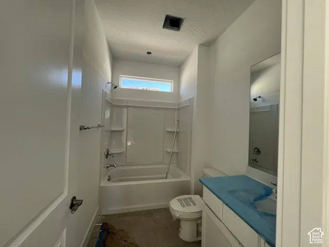 Bathroom featuring a composite tub and shower surround, clerestory window, wall-mounted mirror, and vanity with stone-style countertop
