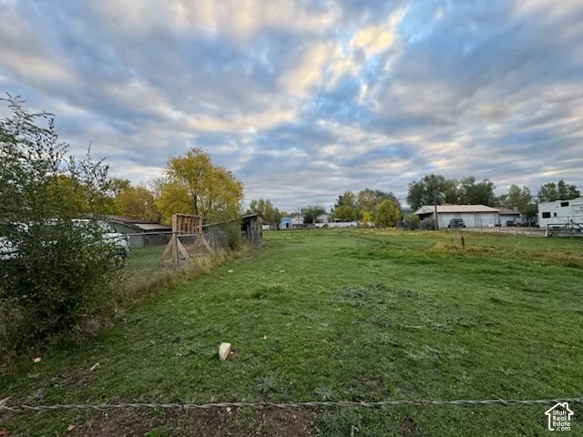 Expansive level lot featuring mature trees, wire fencing, and an open grass area