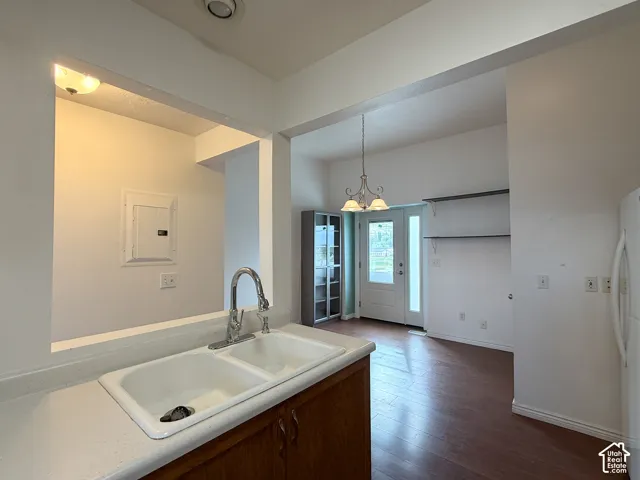 Kitchen area featuring a double-basin sink, high-arch faucet, wood-finish flooring, multi-light chandelier, and built-in wall shelving