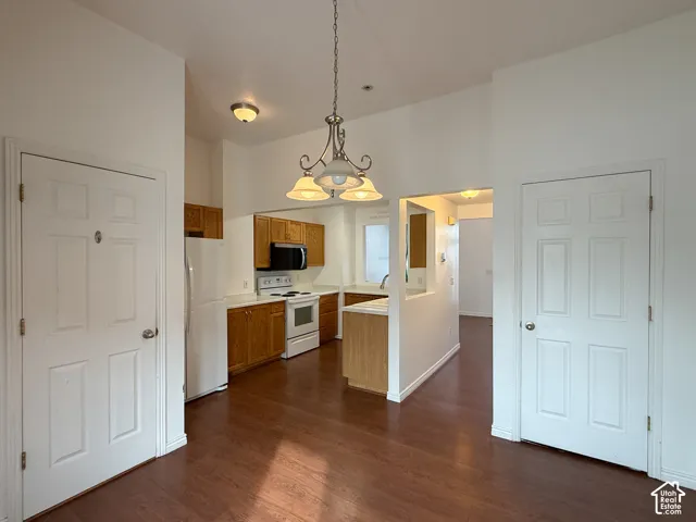 Wood-finish flooring, three-light metal chandelier, white panel interior doors, and wood-finish cabinetry