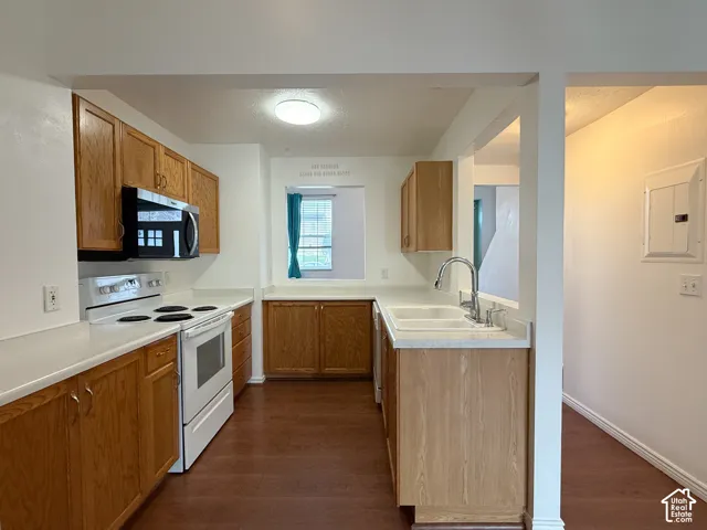 Kitchen featuring wood cabinetry, white countertops, double-basin sink with a gooseneck faucet, built-in microwave, and wood-finish flooring