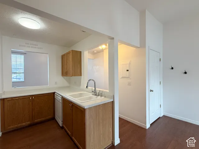 Kitchen featuring wood cabinetry, white countertops, double-basin sink with arched faucet, dishwasher, and wood-finish flooring