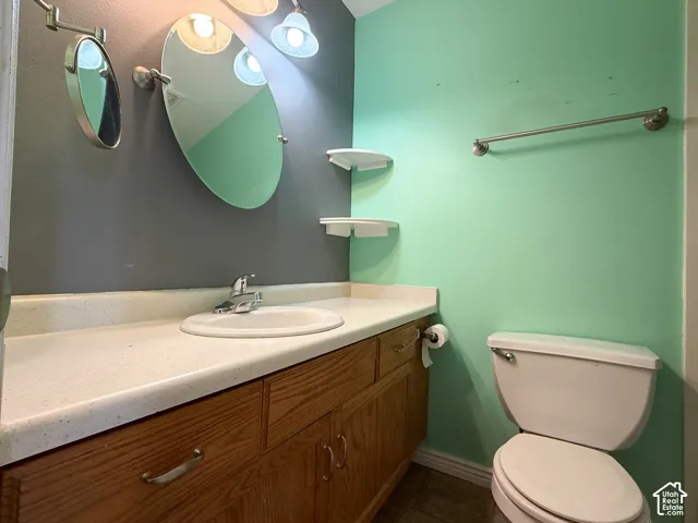 Wood-finish cabinetry featuring a light-toned solid surface countertop, integrated circular sink with a chrome faucet, oval wall-mounted mirror, and tiered corner shelving