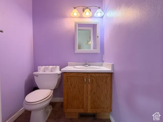 Vanity with wood-finish cabinetry, white countertop, integrated basin, and three-light wall-mounted fixture with a rectangular mirror