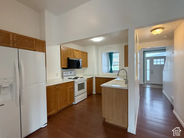 Kitchen featuring wood cabinetry, white appliances, wood-finish flooring, a dual-basin sink with a pull-down faucet, and a pass-through window