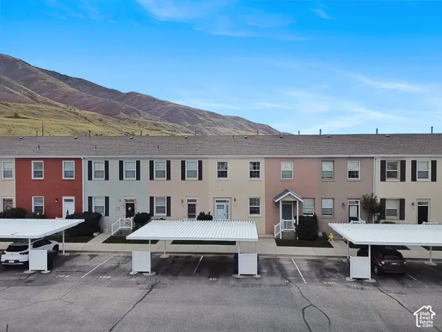 Multi-unit residential exterior featuring a multi-colored facade with contrasting shutters, asphalt shingle roofing, and dedicated covered carport parking