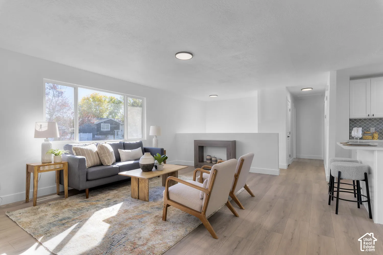 Open concept interior featuring wood-finish flooring, a large picture window, recessed ceiling lighting, and a breakfast bar