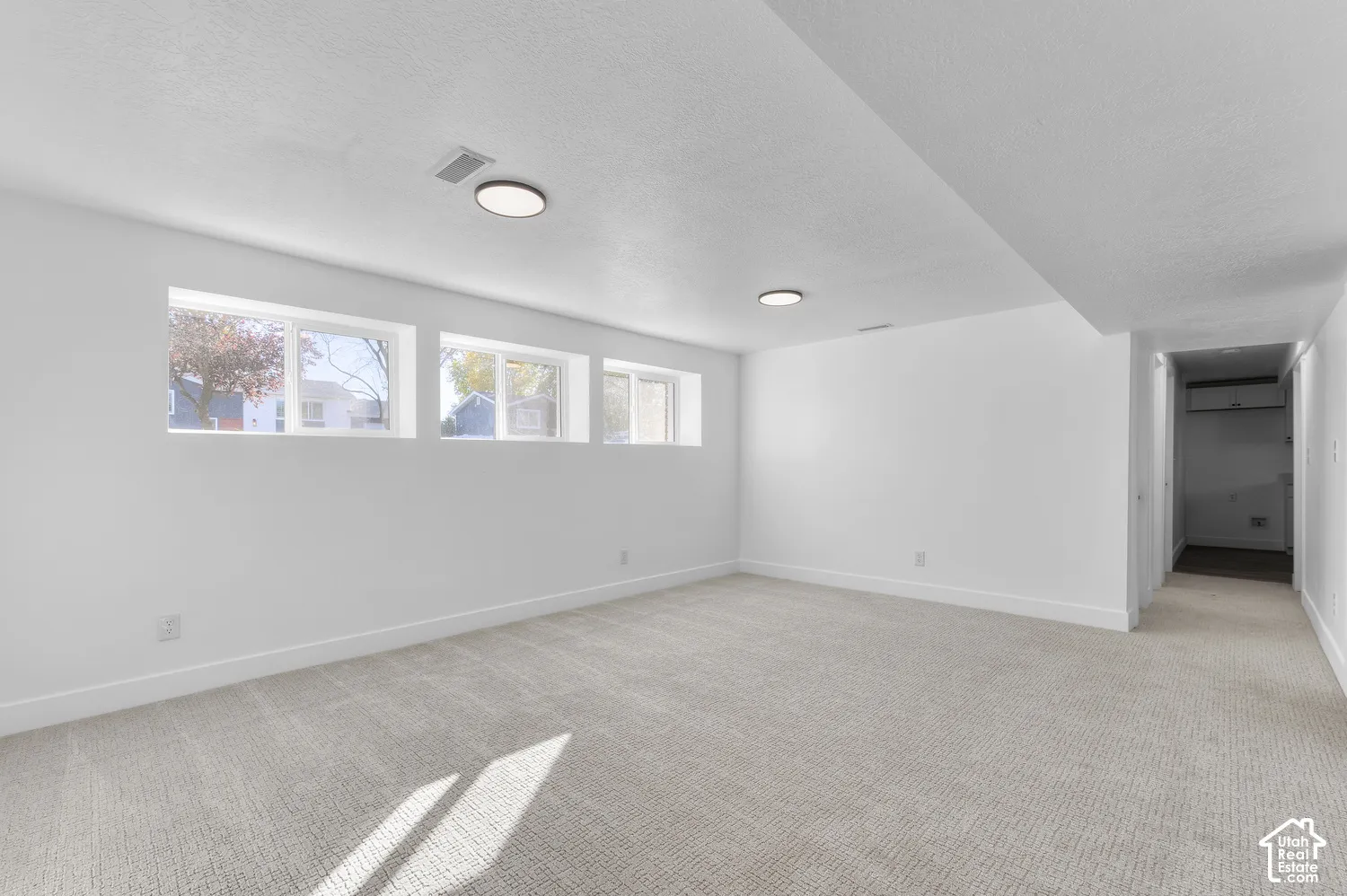 Neutral interior featuring wall-to-wall carpeting, three horizontal windows, and recessed ceiling lighting