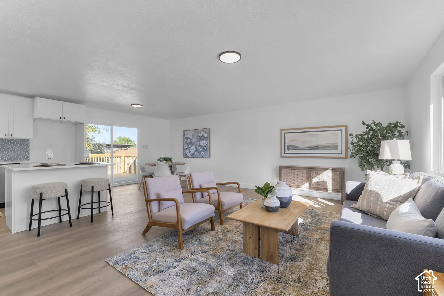 Open-concept interior featuring light wood-finish flooring, a kitchen island with seating, recessed ceiling lighting, and sliding glass doors