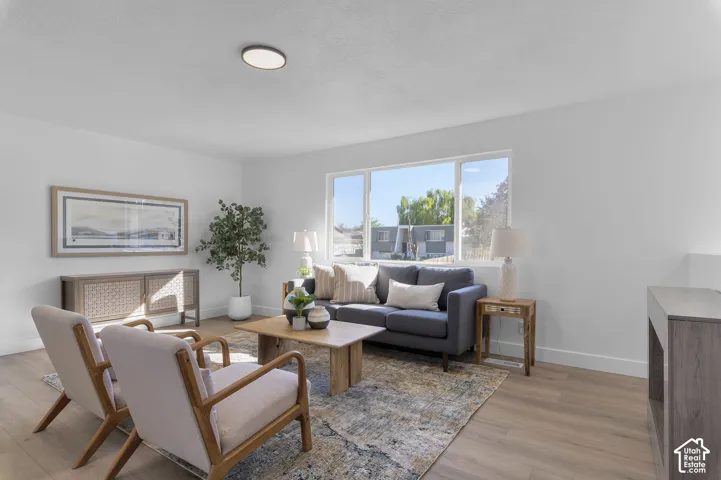 Neutral-toned interior space featuring wood-finish flooring, a large picture window, and a modern flush-mount light fixture