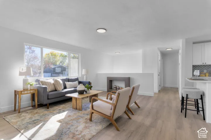 Open concept interior featuring wood-finish flooring, a large picture window, recessed ceiling lighting, and a breakfast bar