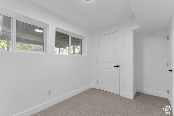 Interior room featuring neutral-toned carpeting, two horizontal slider windows, and two white panel doors with matte black hardware