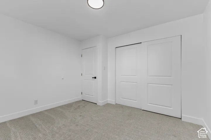 Neutral-toned carpeting, white walls, dual-panel interior door with matte black hardware, and sliding closet doors