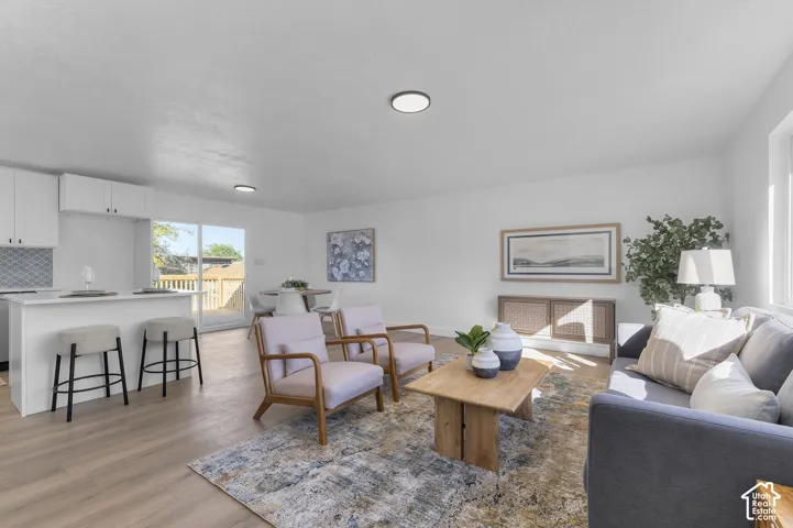 Open-concept interior featuring light wood-finish flooring, a kitchen island with seating, recessed ceiling lighting, and sliding glass doors