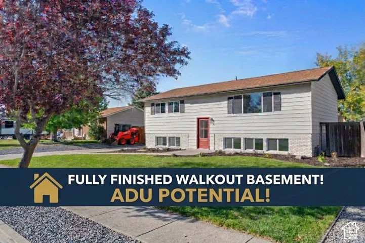 Split-level exterior featuring light-toned horizontal siding, a masonry lower level, a concrete walkway, and a landscaped front lawn