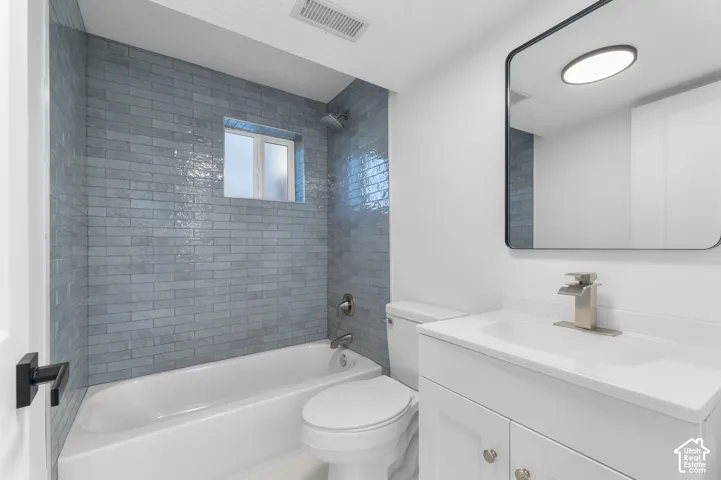 Bathroom featuring blue subway tile surround, white vanity with integrated sink, brushed nickel faucet, and a rectangular mirror with a black frame