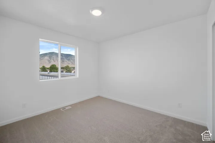 Neutral-toned wall-to-wall carpeting, crisp white wall finish, recessed ceiling lighting, and a sliding window with mountain scenery