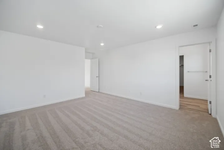 Neutral-toned carpeting, recessed ceiling lighting, and solid-core interior doors