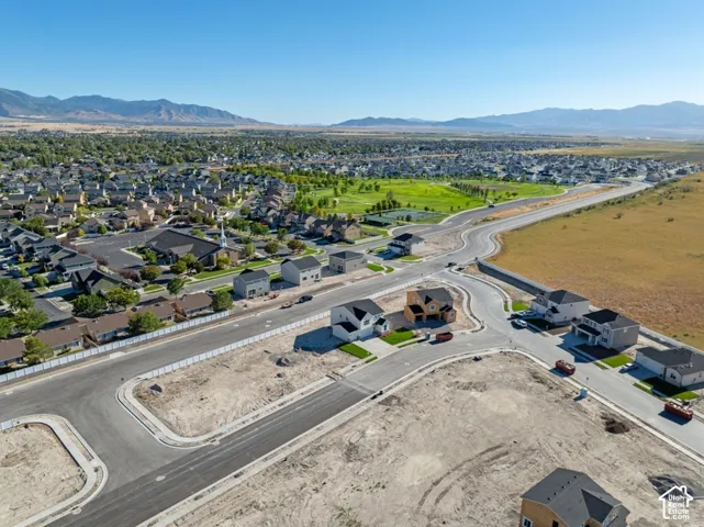 Aerial perspective featuring paved infrastructure, residential development, and expansive mountain range scenery