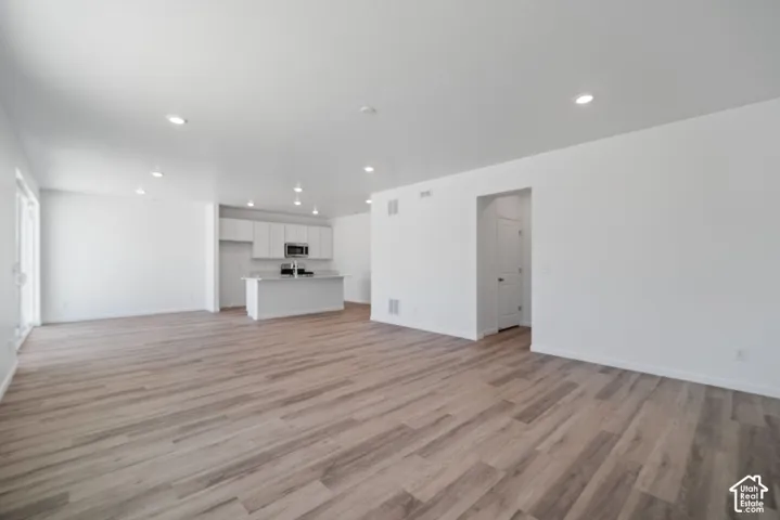 Open-concept living space featuring wood-finish flooring, recessed lighting, and kitchen cabinetry with a central island